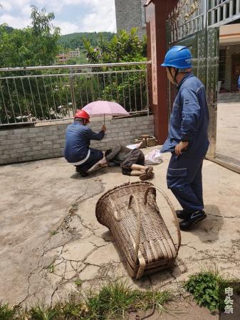 赵伦同志为老人打开雨伞制造阴凉休息环境