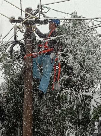 为保障群众稳定用电，供电人员冒雪抢修线路。