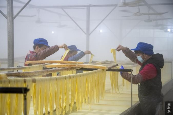 2、2022年3月1日，在广西梧州市苍梧县京南镇梧州市恒润食品腐竹厂生产车间内，工人忙着晾晒腐竹。（何华文）