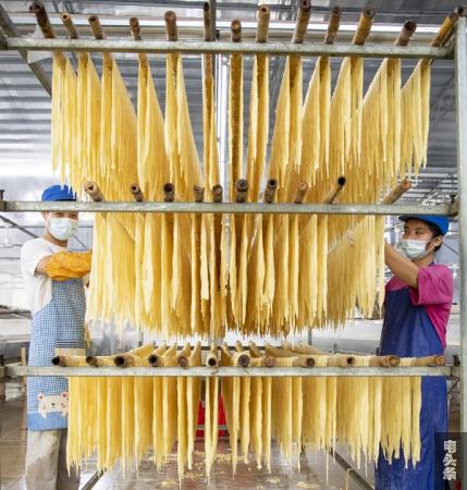 10、2022年3月1日，在广西梧州市苍梧县京南镇梧州市恒润食品腐竹厂生产车间内，工人忙着晾晒腐竹。（何华文）