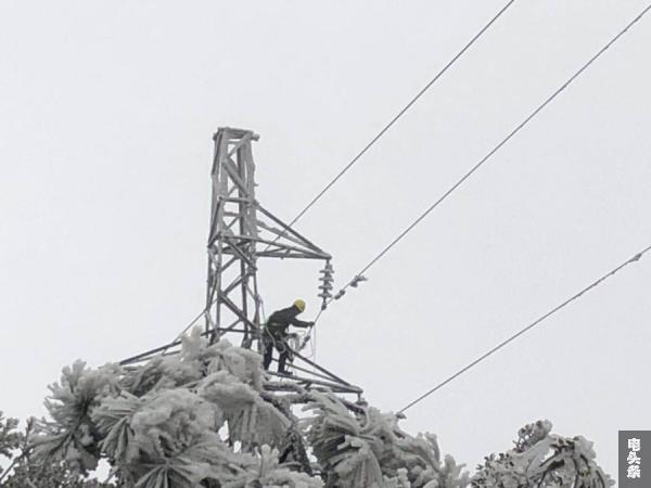 除冰人员登上覆满冰雪的铁塔上敲冰。 赵英 摄2