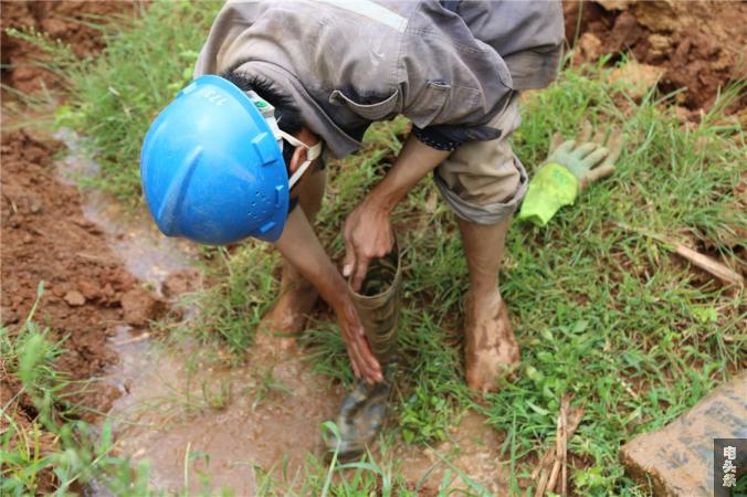 抢修完成后，一名现场人员正在用泥水清洗沾满泥土的水靴。平东宁 摄