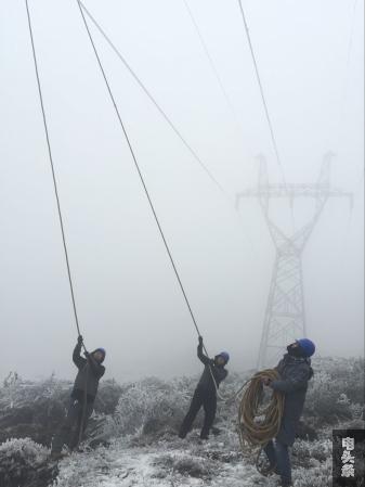 在宣威，供电员工在冰雪中用绳索拉去导线上的冰。（董学贤 摄）_副本