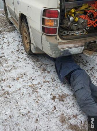 巡线员为了确保交通安全，爬到雪地上检查防滑链是否牢固。 董何波  摄